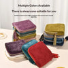 A collection of velvet jewelry organizer pouches in various colors including purple, green, pink, and red stacked on a white 