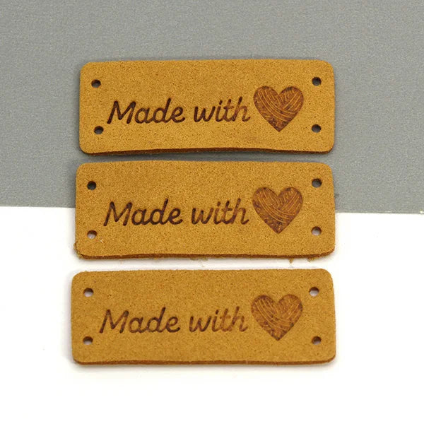 Three rectangular brown leather labels with the text Made with and a heart design.
