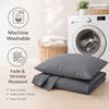 A stack of gray microfiber pillowcases and a washing machine are shown on a wooden surface.