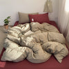 A set of minimalist striped 100% cotton duvet covers in beige and pink tones displayed on a bed.