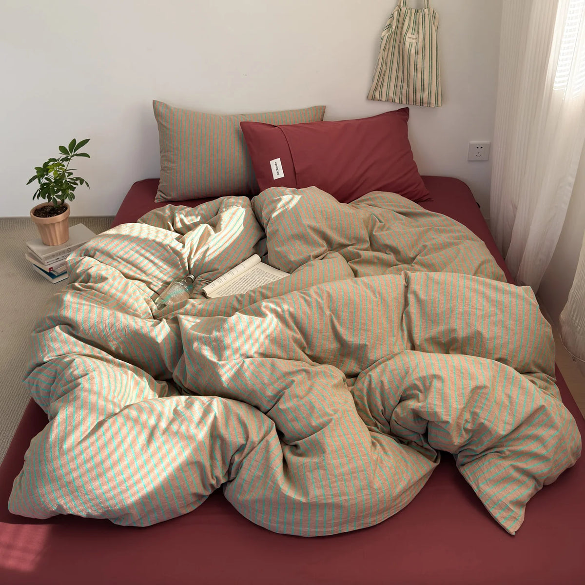 A set of minimalist striped 100% cotton duvet covers in beige and pink tones displayed on a bed.