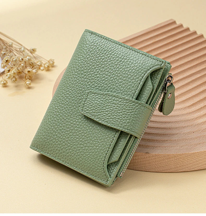 A light green genuine leather RFID blocking bi-fold wallet resting on a wooden surface.
