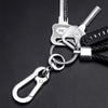 Silver keychain featuring a key, a phone number tag, and a braided black leather rope.