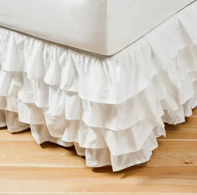 White ruffled bed skirt wrapping around a mattress to hide under-bed space