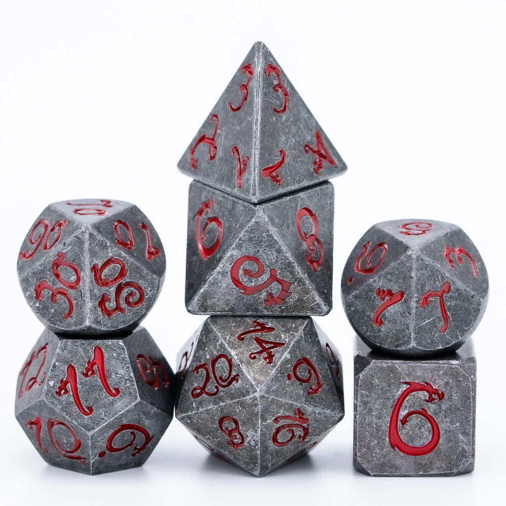 A set of seven gray metal polyhedral dice featuring a red dragon font design.