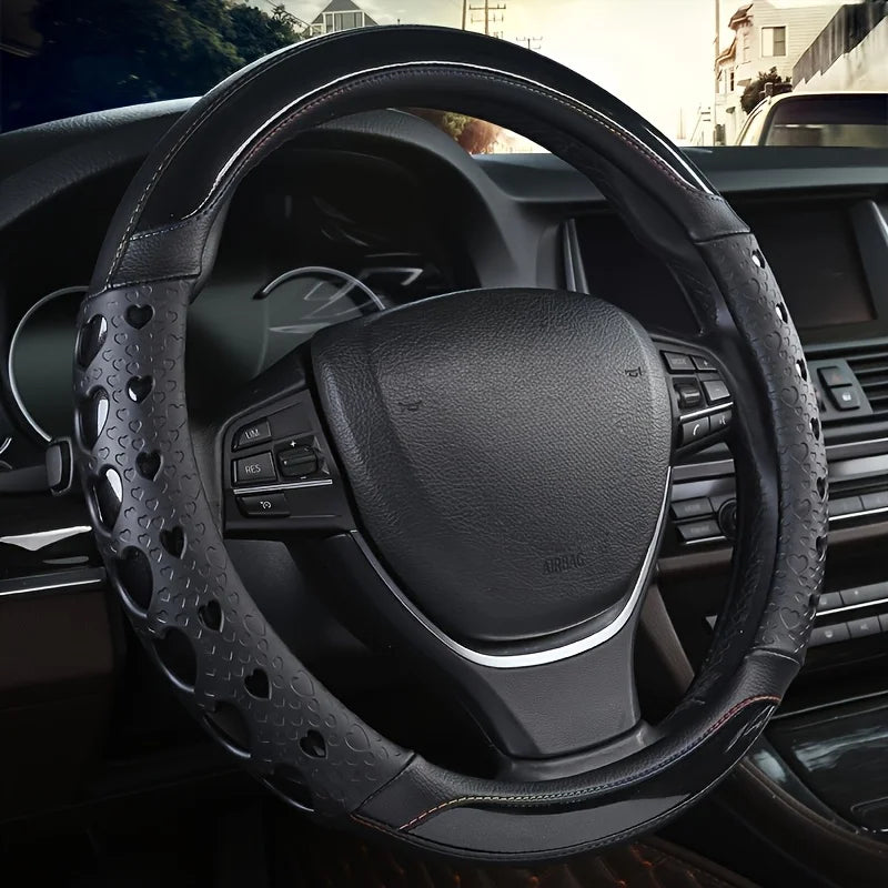 A close-up view of a black heart-shaped steering wheel cover in soft PU leather inside a car