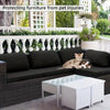 Dunkelgraue Outdoor-Sofa mit schwarzen Kissen und einem Glastisch in einem Wohnbereich.