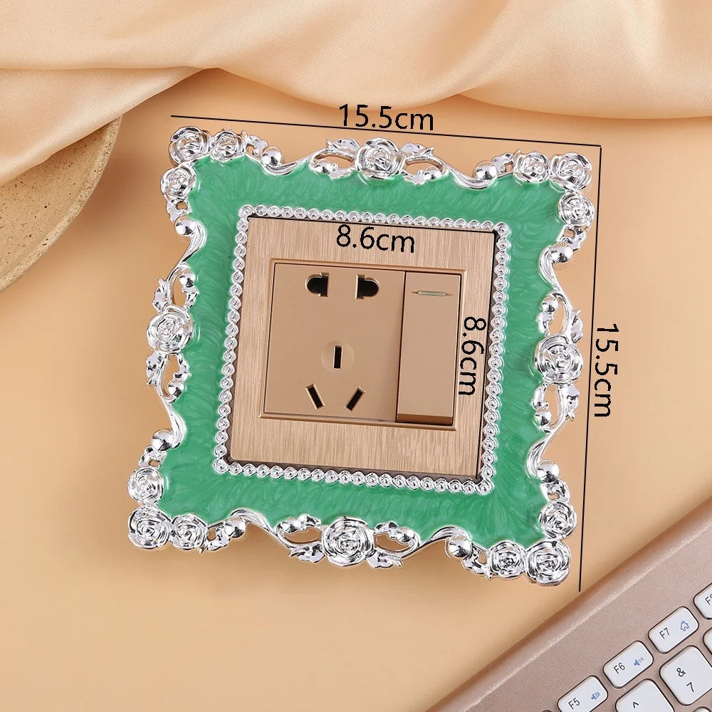 A rectangular switch cover frame with a rose pattern border and gold finish, shown against a beige background.