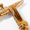 A close-up view of a gold-plated brass tenor saxophone mouthpiece with intricate patterns.