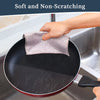 A hand is using a soft, non-scratching cleaning cloth to wipe a black frying pan in a kitchen sink.