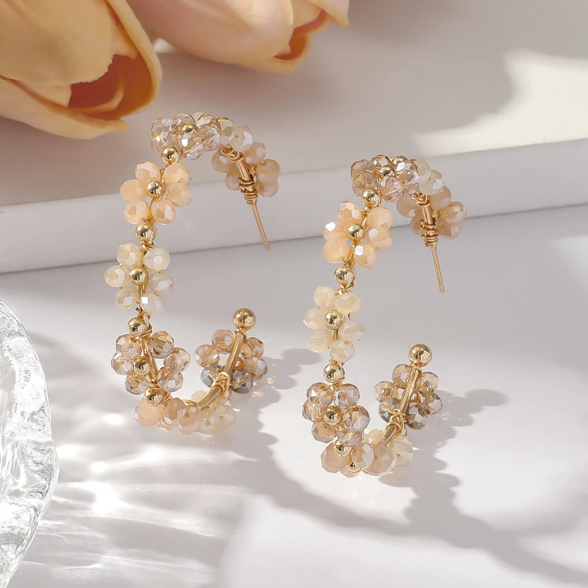 Gold and cream beaded sunflower drop earrings displayed on a white surface.