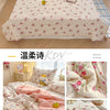 A pink floral quilt with a yellow cartoon bear design displayed on a bed.