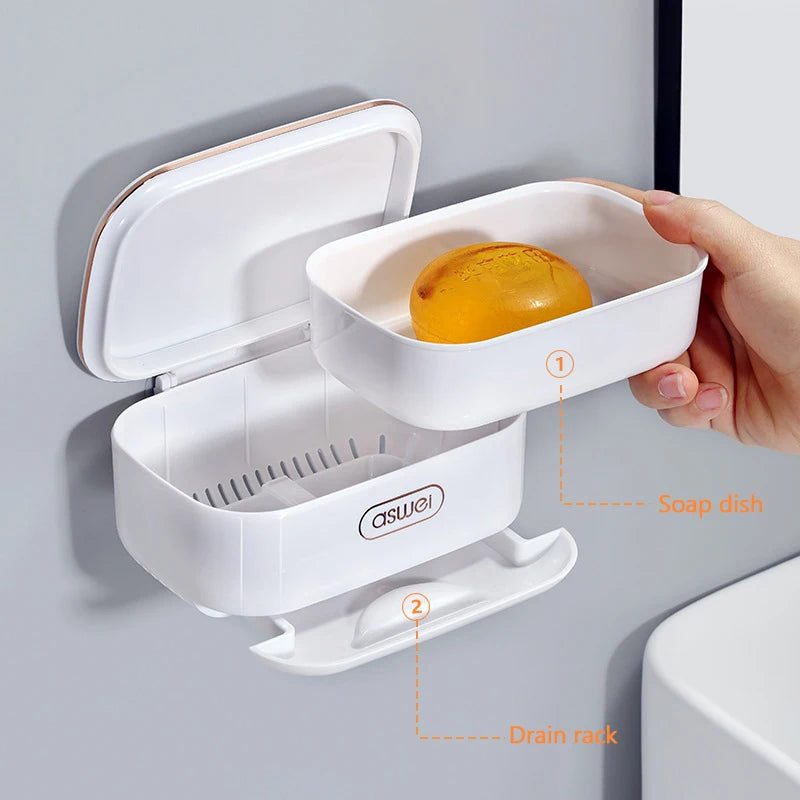 A white two-tier draining soap holder with a soap dish and drain rack mounted on a wall.