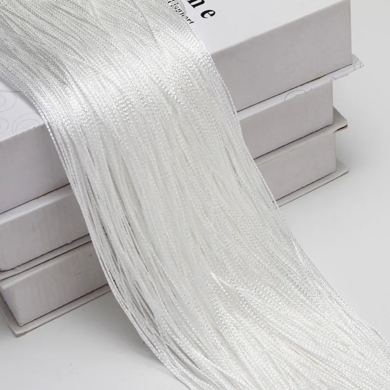 A long, sheer white beaded thread curtain draped over a box.