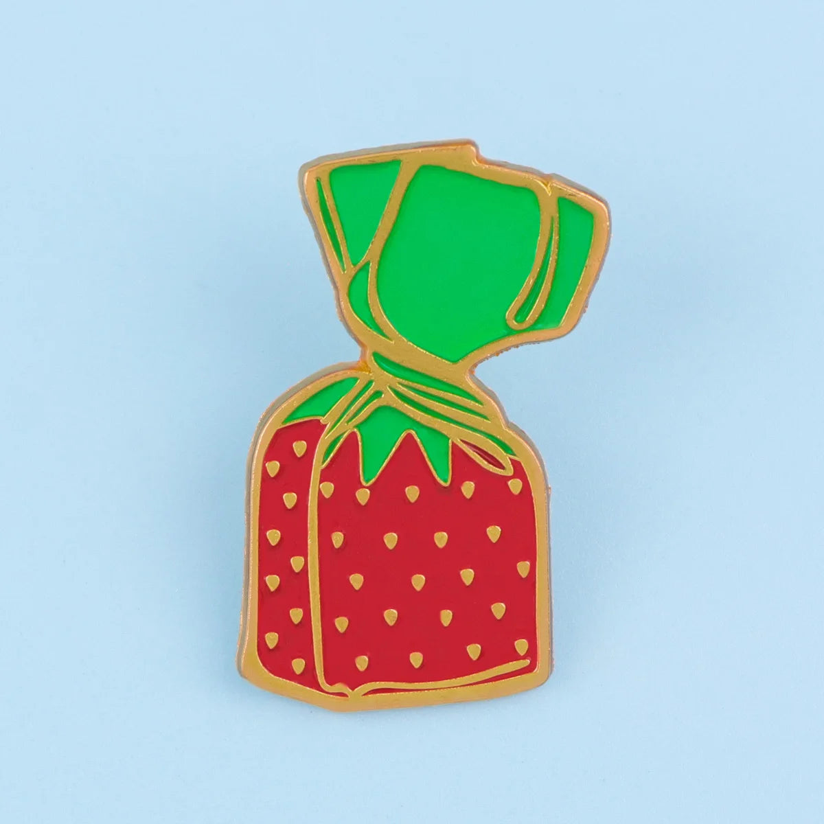 A gold-rimmed enamel pin shaped like a strawberry with a green top and a yellow-wrapped stem.