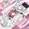 A pink and black anime-themed mouse pad or desk mat featuring characters and artwork.