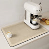 A white espresso machine is placed on a beige counter mat with coffee cups and bread visible.