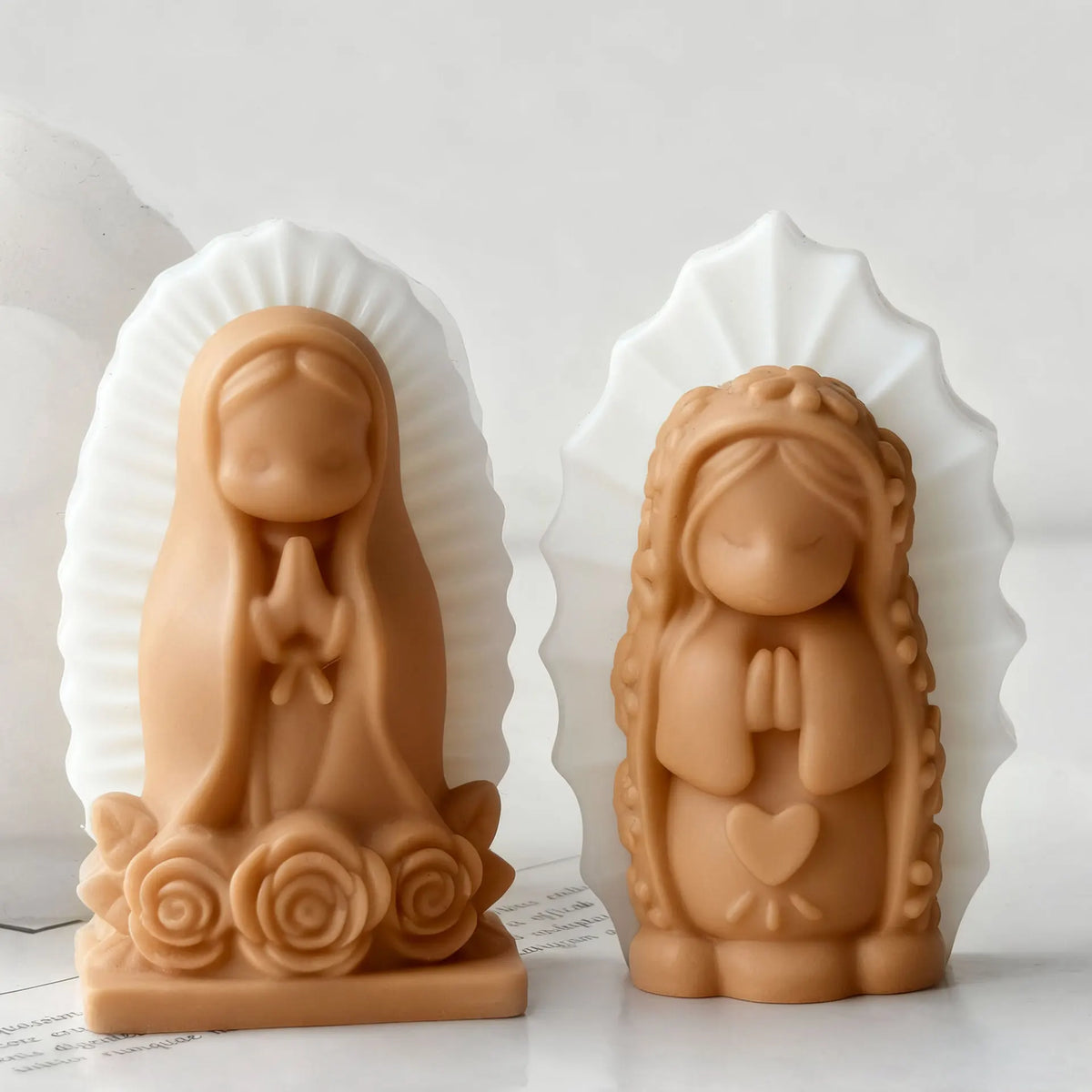 A terracotta silicone mold of a praying girl with hands clasped, set against a white fan-shaped background.