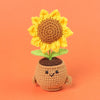 Handcrafted crochet sunflower with green leaves growing out of a brown pot