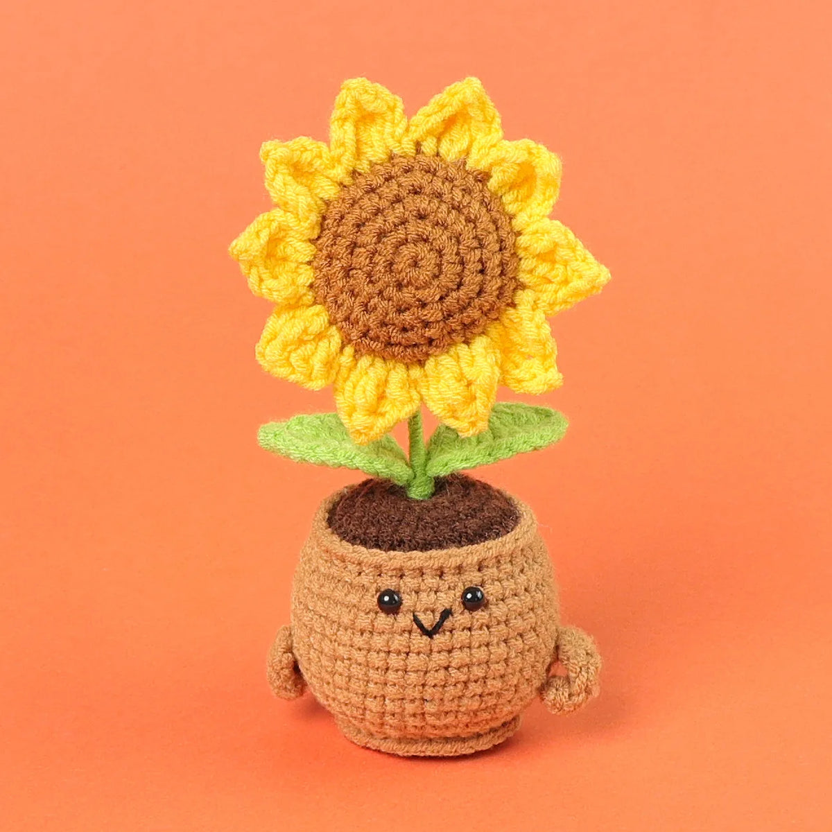 Handcrafted crochet sunflower with green leaves growing out of a brown pot