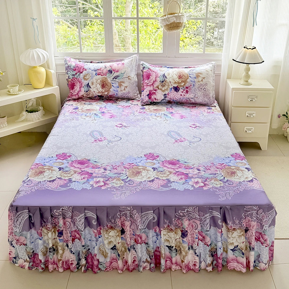 A floral print bed skirt and pillowcase set featuring pink, purple, and white flowers.