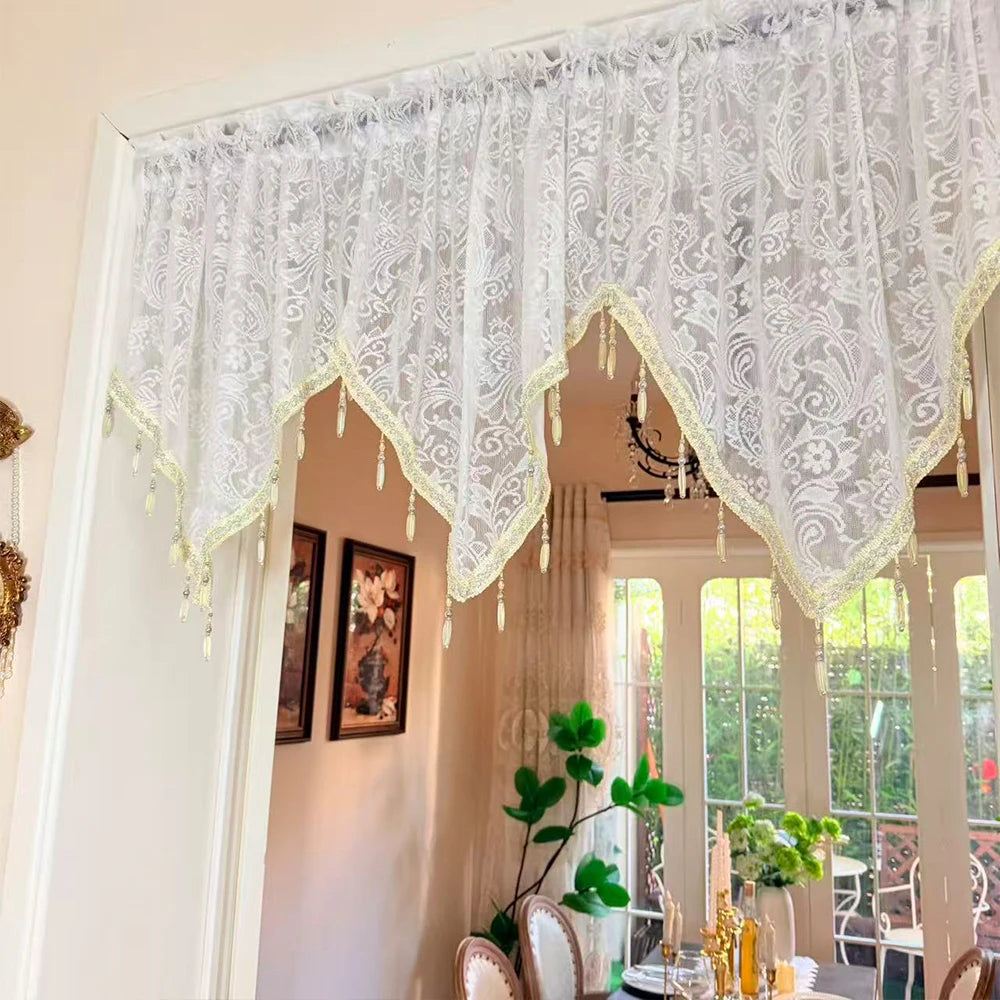 White lace curtain valance with irregular black window pendants framing a light-filled room.