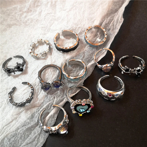 Eine Kollektion von Punk-Kristall-Herz-Schmetterlings-Geometrie-Ringen auf weißem Stoff.