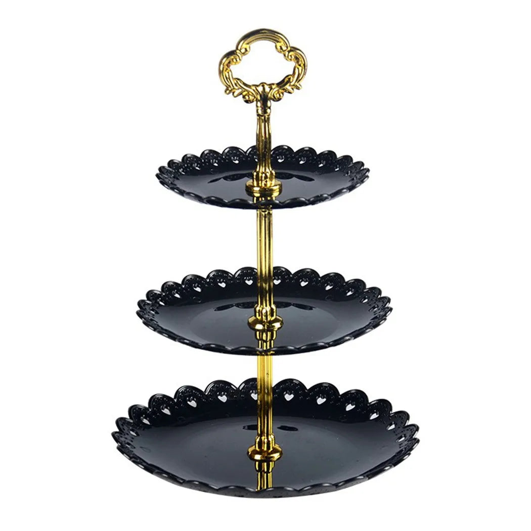A three-tier gold and black acrylic cake stand with decorative scalloped edges.