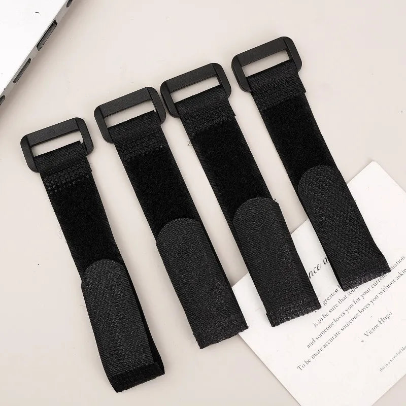 Four black reusable nylon cable ties with adjustable hook and loop fasteners displayed on a white background.