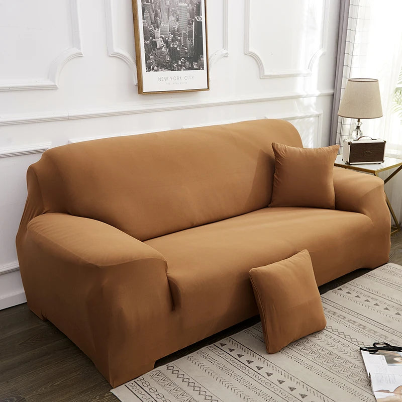 A tan silky soft stretchable sofa cover displayed on a couch in a bright room.