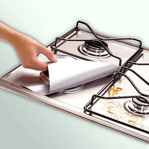 A hand is placing a white liner into a square gas hob protector pan.