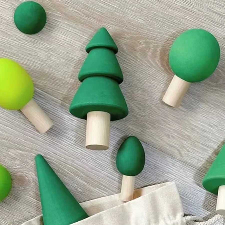 A collection of green and lime colored wooden stacking blocks shaped like trees, resting on a light wooden surface.