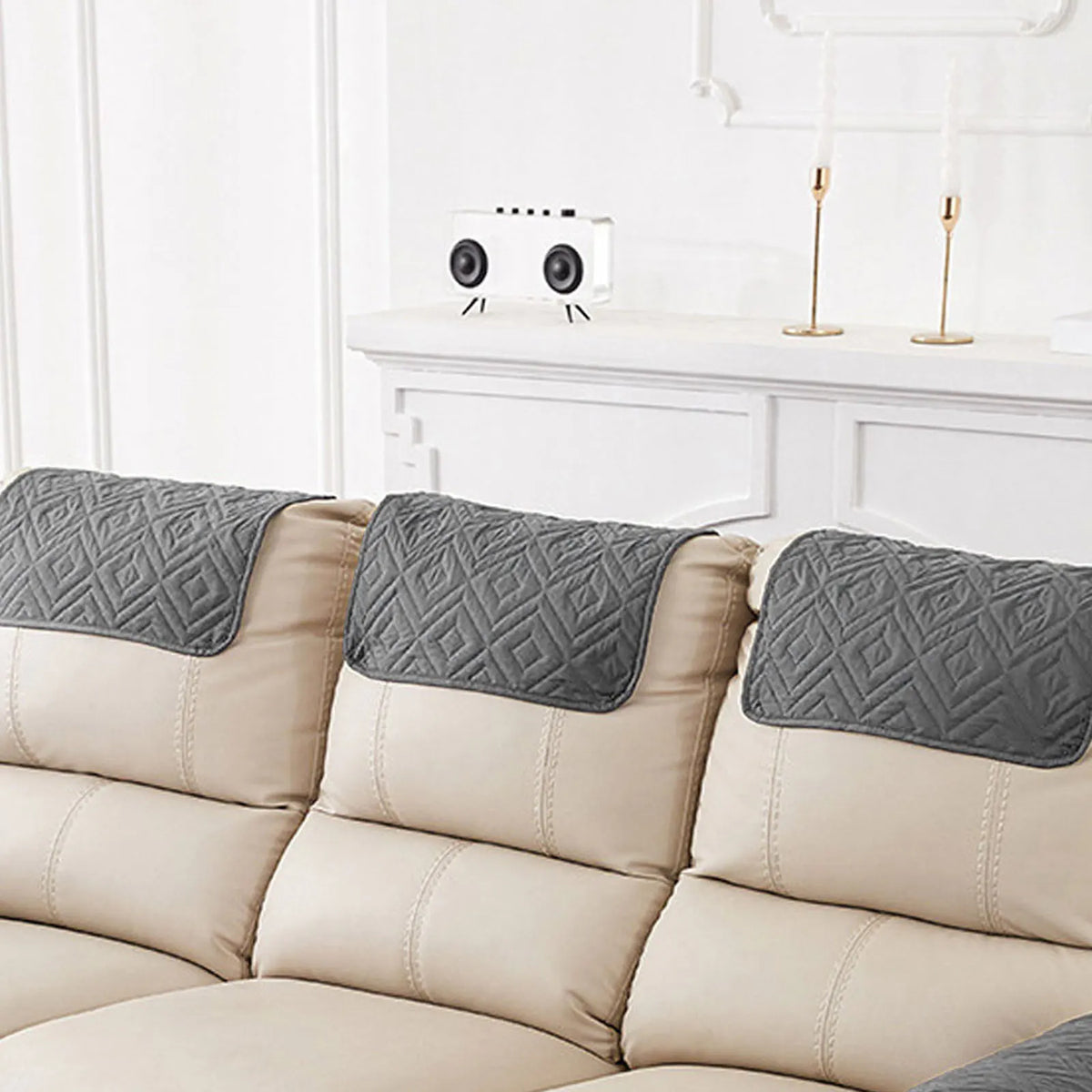 Three gray headrest protector covers for a beige recliner sofa.