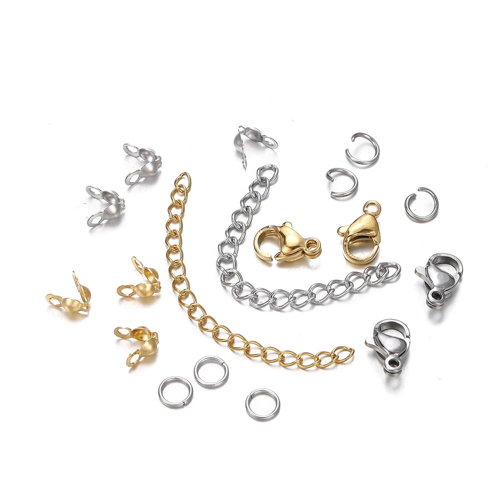 A collection of silver and gold jewelry components including lobster clasps, jump rings, and crimps.