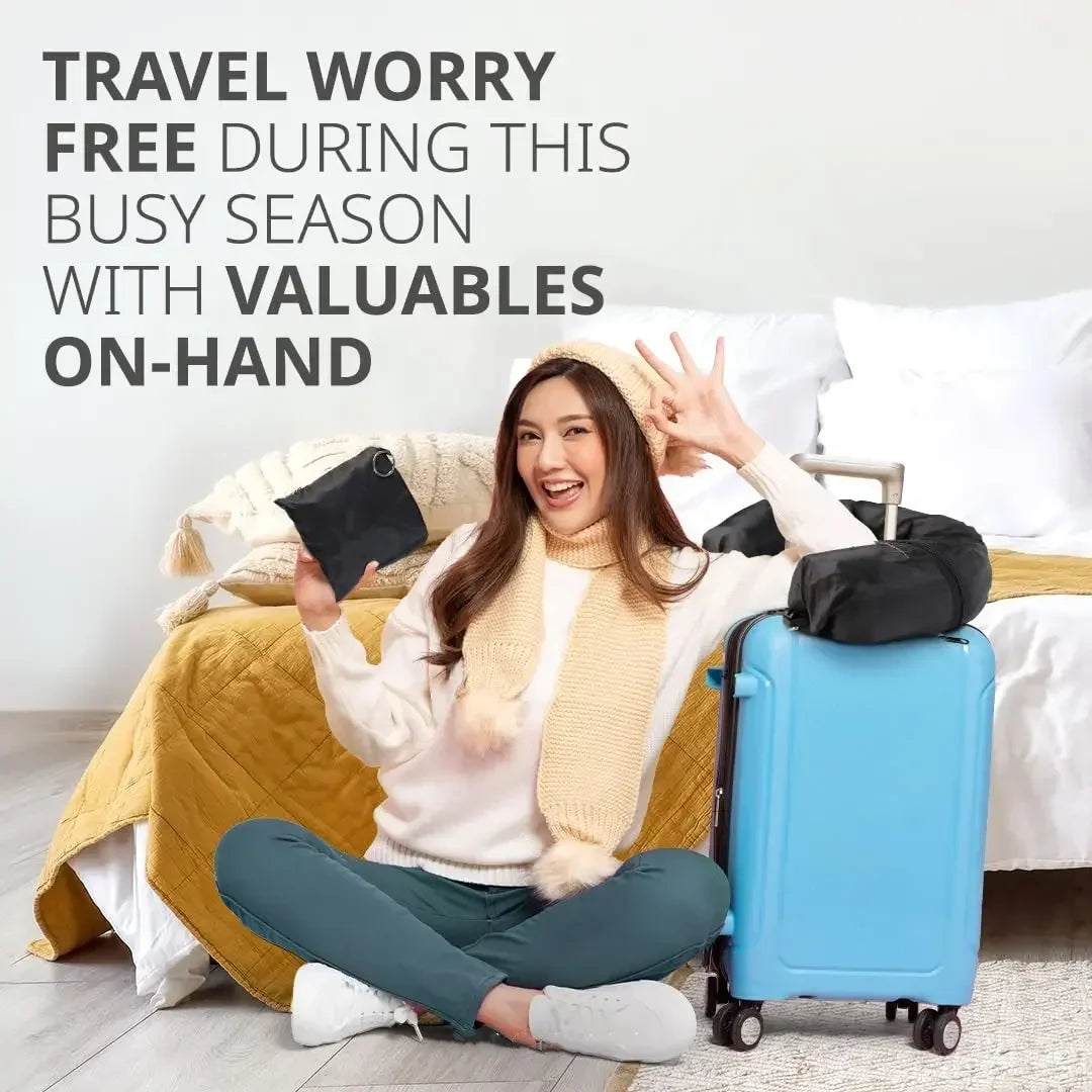 A smiling woman wearing a cream sweater is sitting on a bed with a blue suitcase and a yellow blanket.