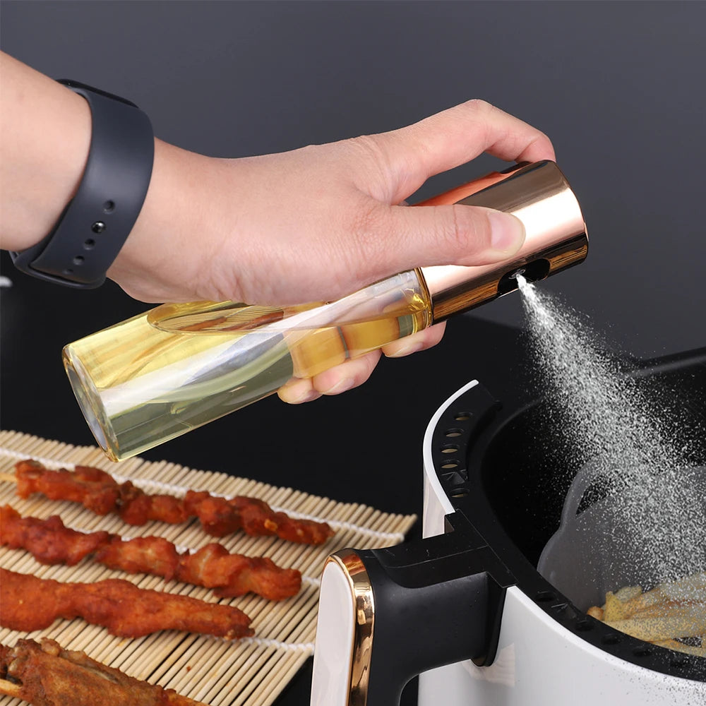 Eine Hand sprüht Öl aus einer Glasflasche in einen Kochtopf, das demonstriert eine wiederverwendbare Ölsprühflasche für gesun