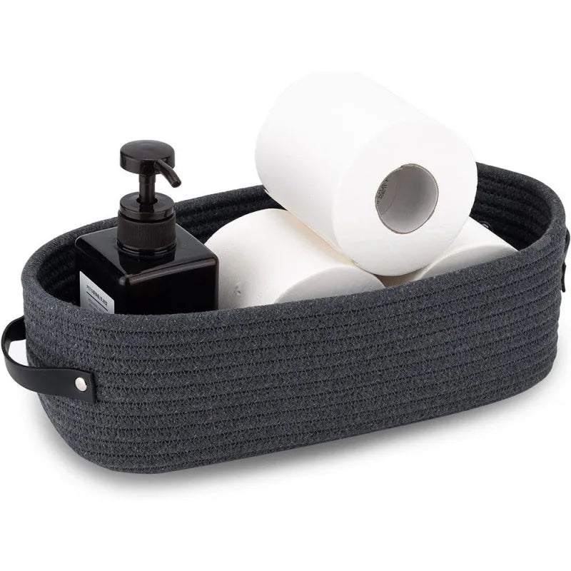 A dark gray woven cotton rope storage basket filled with white toilet paper rolls and a black dispenser.
