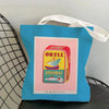 A blue canvas tote bag with a pink label featuring a graphic of sardines and the text Ortiz Sardinas a la Antigua