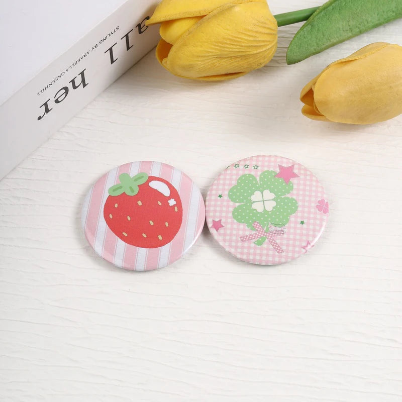A set of playful tinplate pins featuring strawberry and clover designs on a white background.