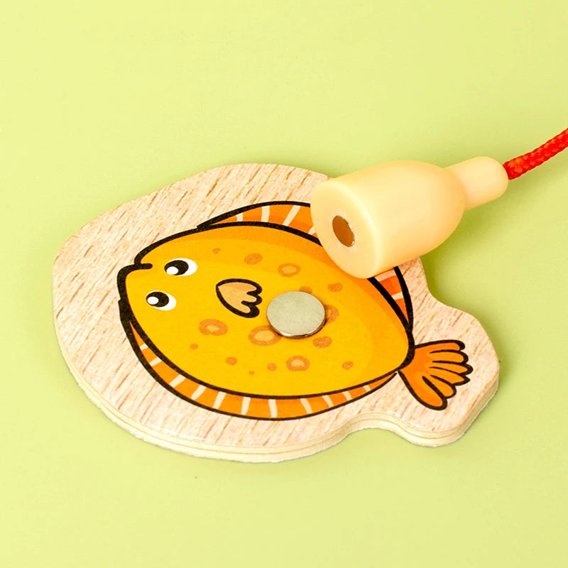 A wooden magnetic fishing game toy shaped like a yellow fish with an attached string.