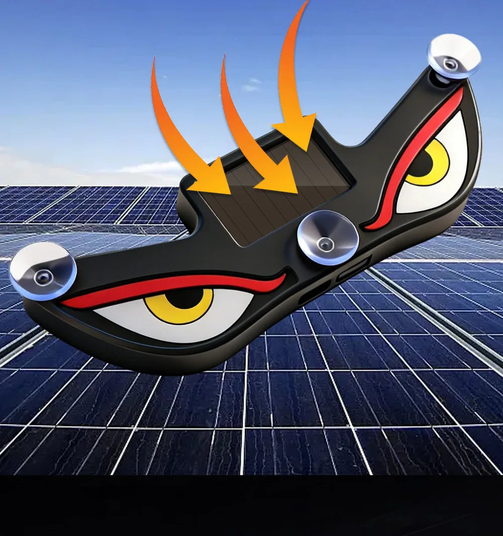 A black, eye-shaped solar-powered LED car window decal is shown resting on a blue solar panel surface.