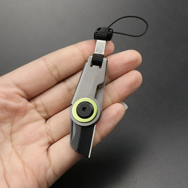 A hand holds a compact folding pocket knife with a keychain attachment, showing the blade and handle.