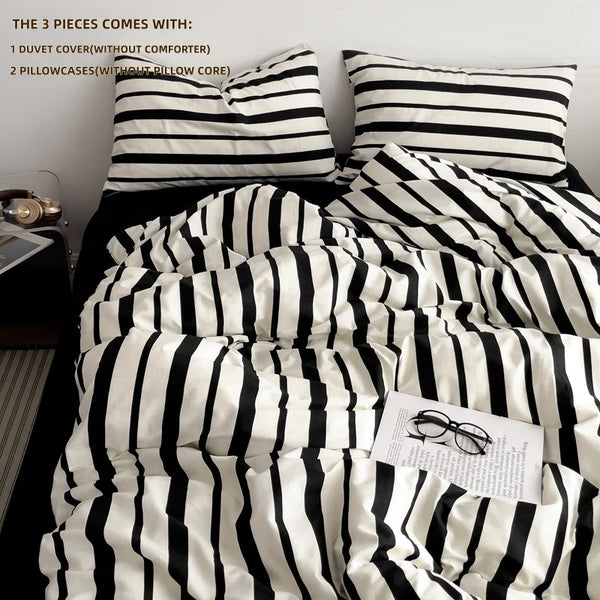 A black and white striped duvet cover set displayed with pillows and a pair of eyeglasses.