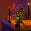 An LED Halloween birch tree decorated with orange and purple lights on a table.