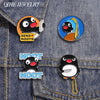 Enamel pins featuring cartoon penguins and text like SEND NOOTS on a denim fabric background