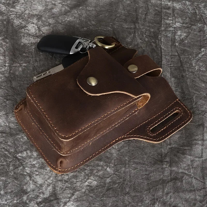 A brown genuine leather waist bag with multiple pockets and a metal clip is shown on a gray textured background.