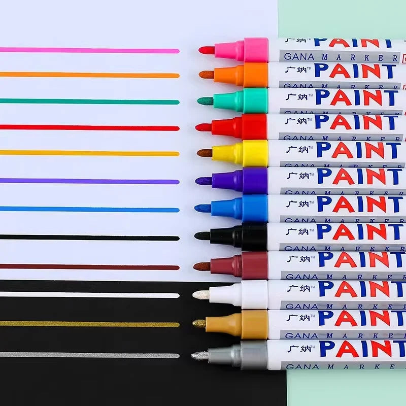 A collection of various colored paint markers and touch-up pens lined up on a white surface.
