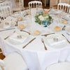 Elegant white satin round tablecloth set for a wedding or event dinner table.