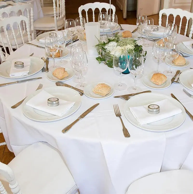 Elegant white satin round tablecloth set for a wedding or event dinner table.