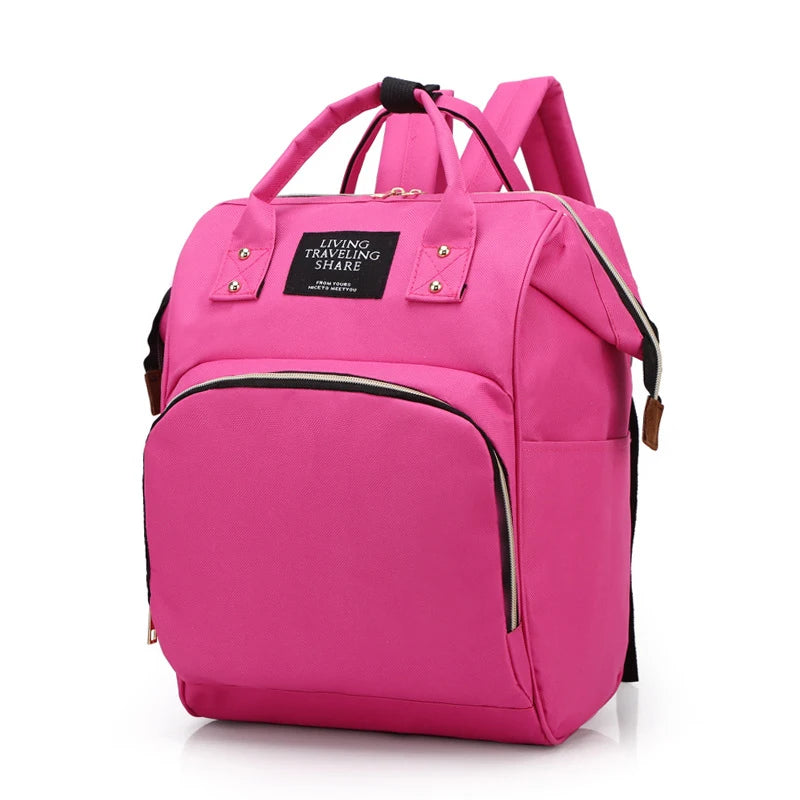A pink insulated canvas mummy diaper bag with a black strap and hanging hook.